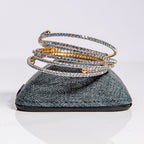March aquamarine birthstone bangles in gold with blue crystals stacked to demonstrate flexible fit
